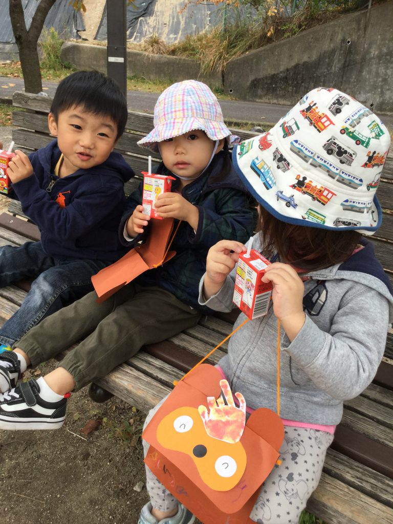 お散歩中、公園のベンチに座ってアンパンマンジュースを飲んでいる写真