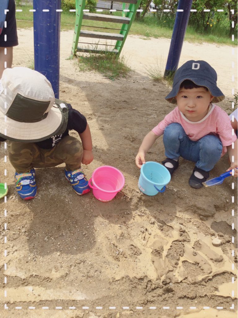 雨上がりの滑り台下の土で泥んこ遊びをしている園児たち