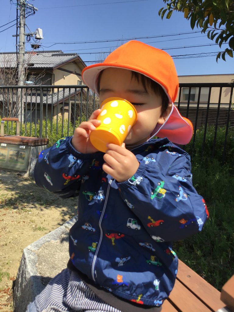 コップで水分補給する園児