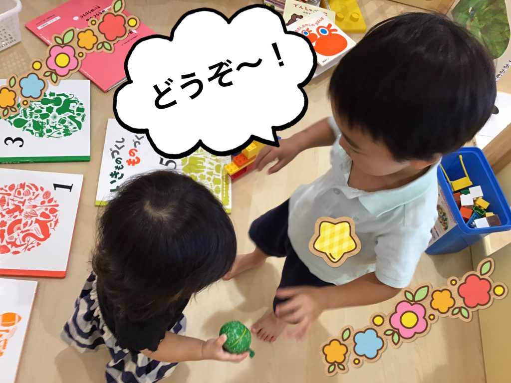 小さい子におもちゃを貸してあげている園児