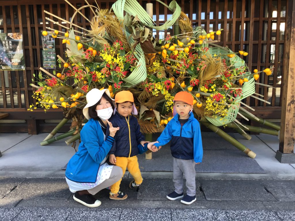 大きい花と一緒に記念撮影する保育士と園児