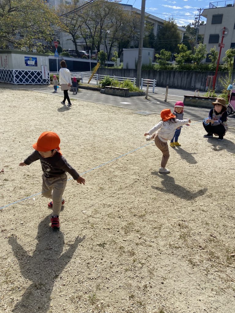 公園で弾かれた紐を乗り越える園児たち