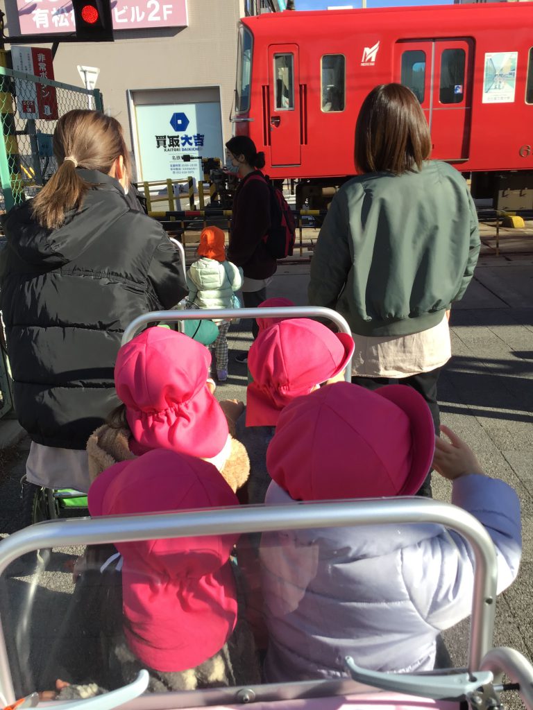 踏切で電車を見送る園児