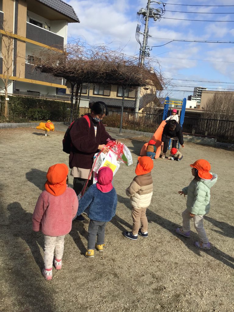 公園で凧を配られるのを待つ園児