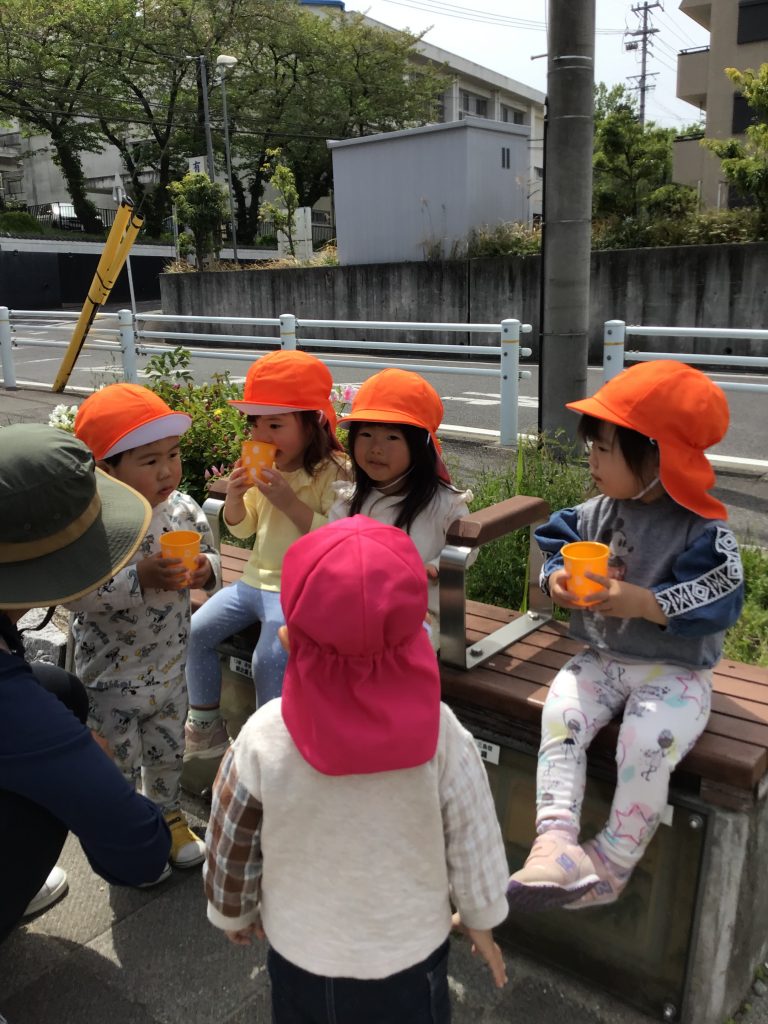 ベンチに座って水分補給する園児