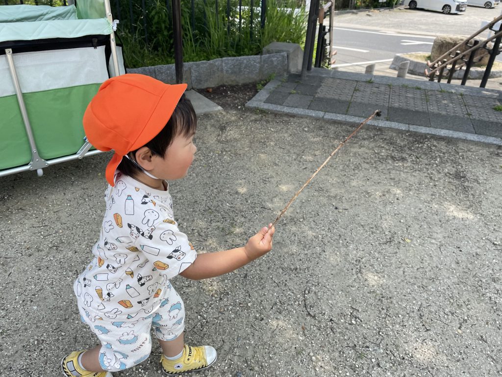 ぼうに捕まった虫を見つめる園児