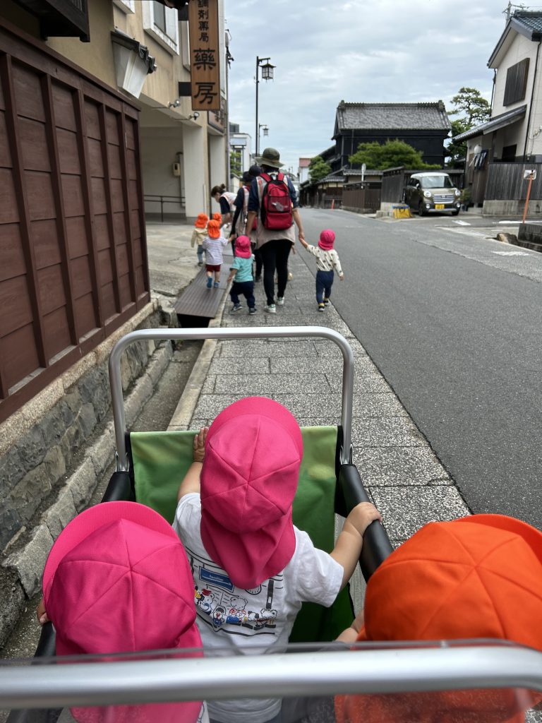 手をつないで歩く園児とお散歩車で散歩する園児