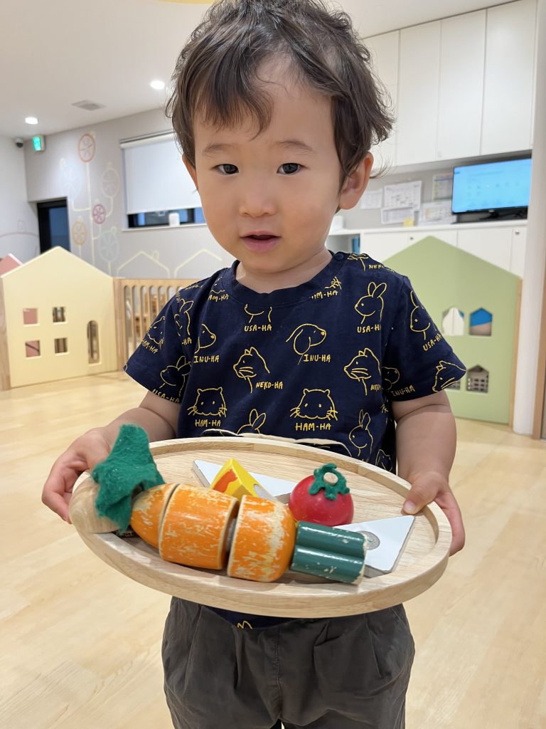 おままごとで使う食べ物を運んでいる園児