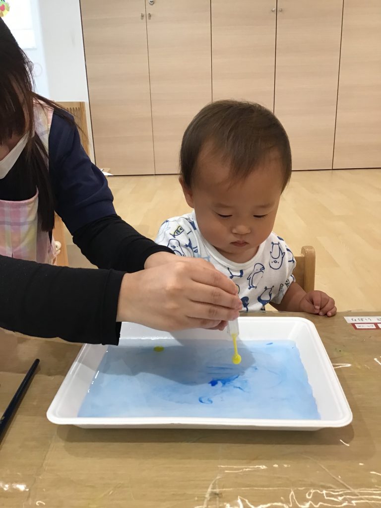 水の張った箱に絵具を垂らす園児