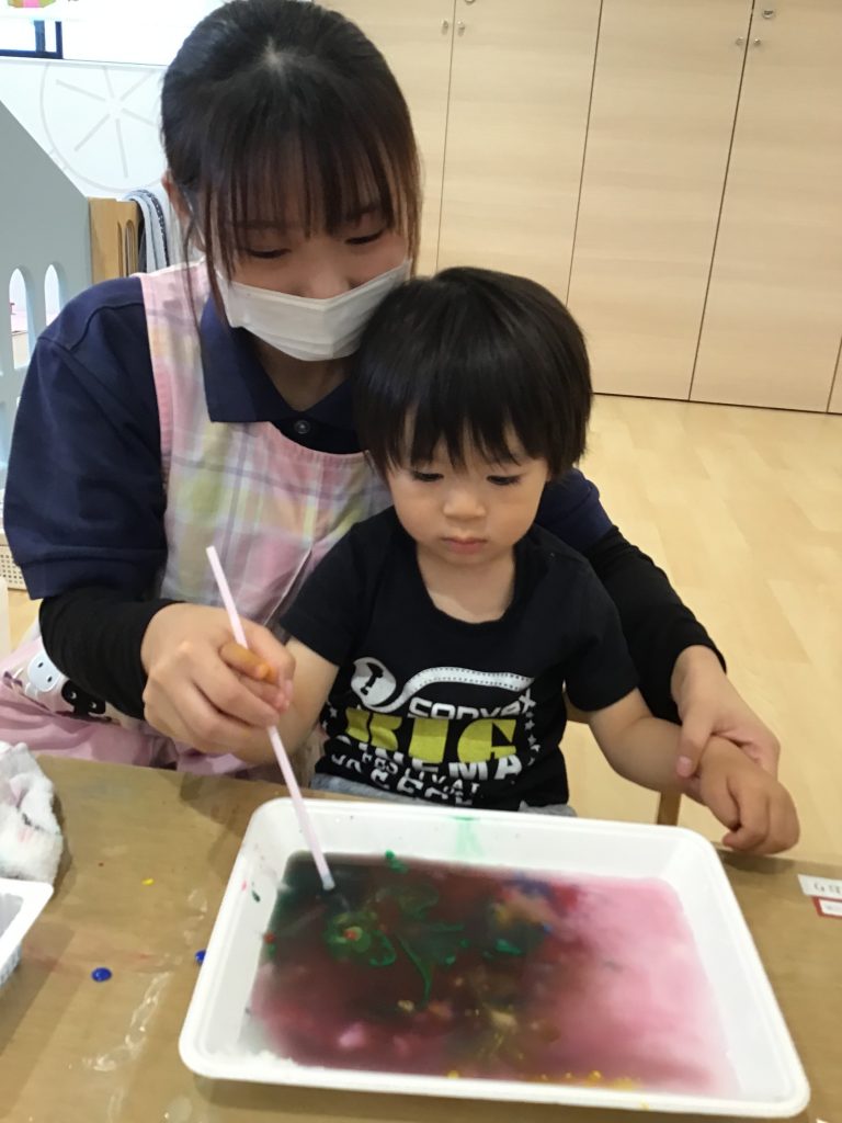 水の張った箱に絵具を垂らす園児