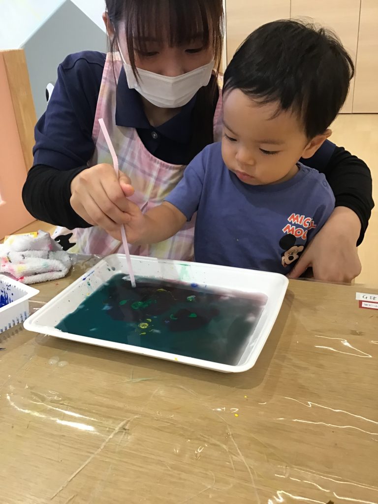 水の張った箱に絵具を垂らす園児