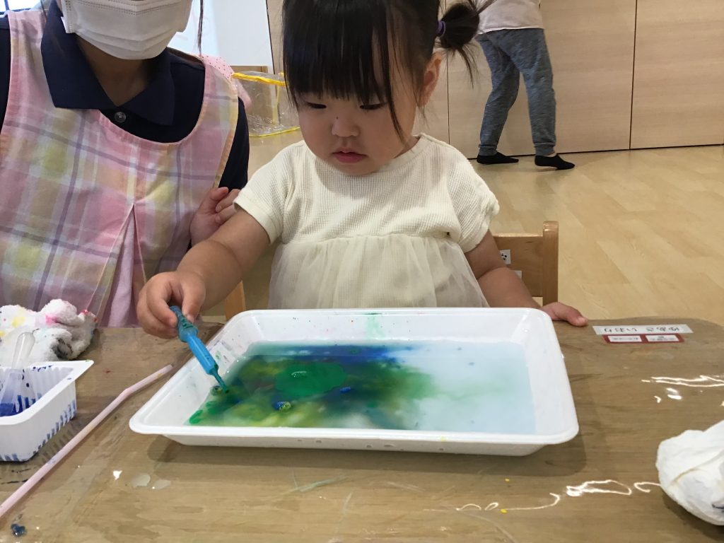 水の張った箱に絵具を垂らす園児