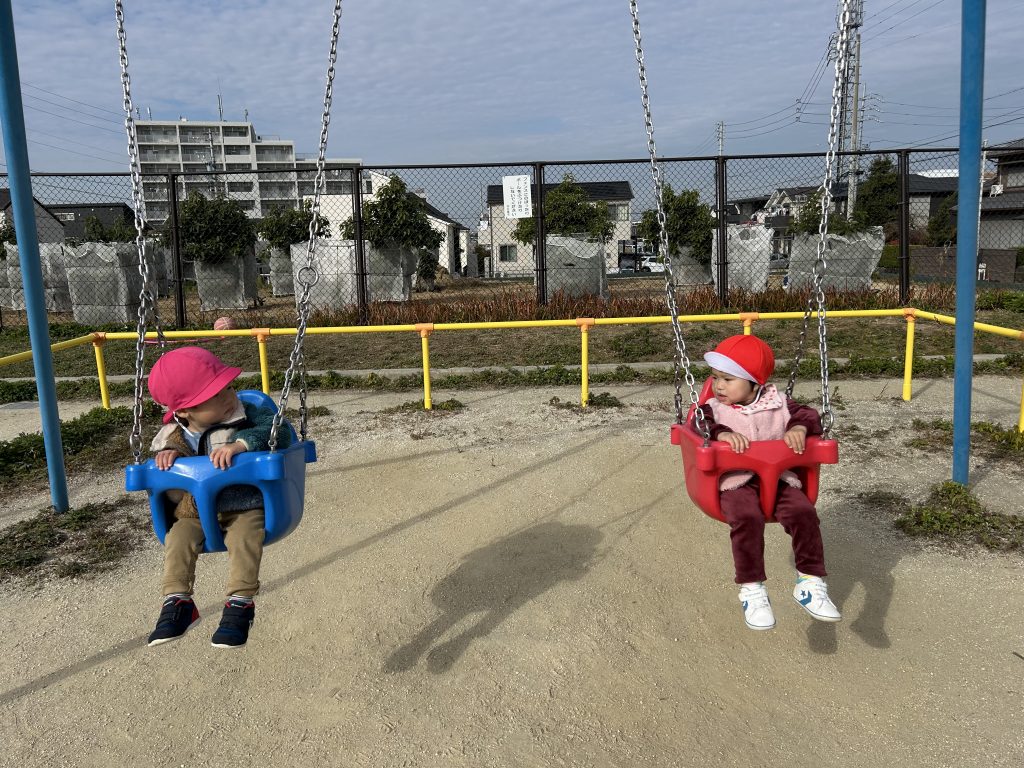 ブランコに乗って見つめ合う園児2人