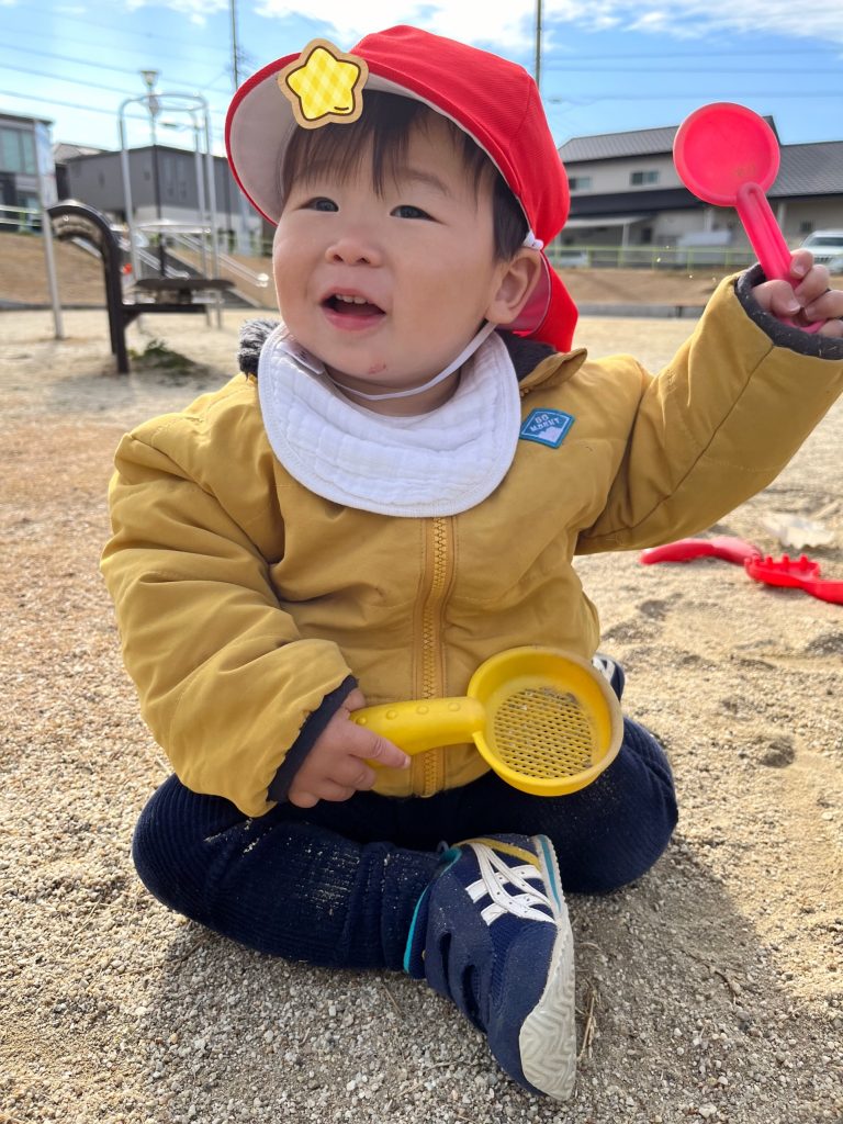 砂場のおもちゃを持つ園児