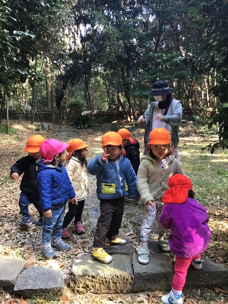 木々に囲まれた場所でポーズを取る園児