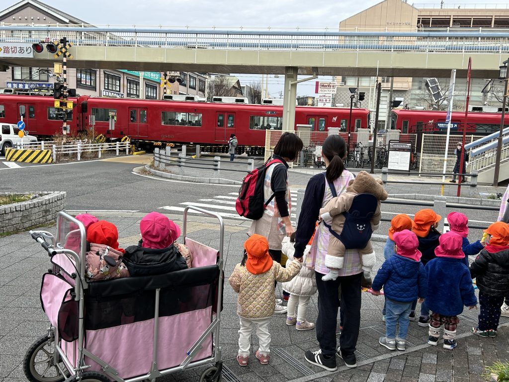 散歩中に電車を見つめる園児たちの後ろ姿