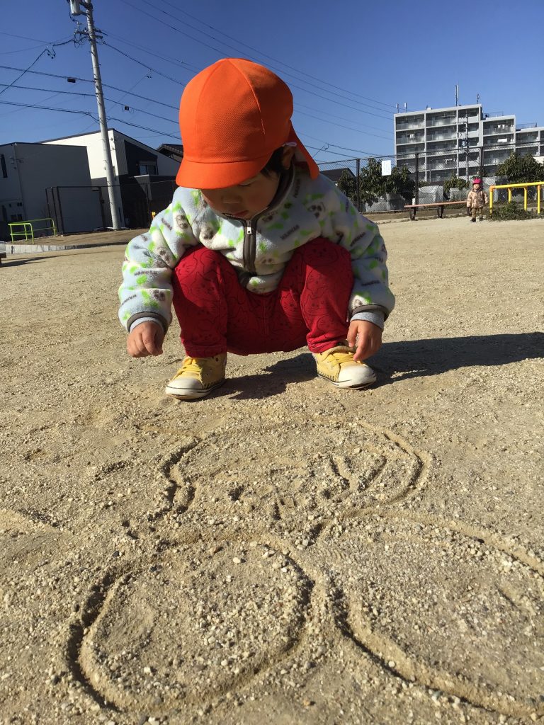 公園の地面に絵をかく園児